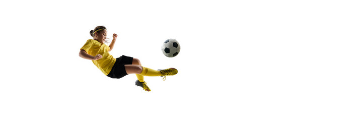 Dynamic image of girl, soccer player in yellow jersey and black shirt during game, training, kicking ball in jump and falling down against white background. Concept of sport, childhood, competition,