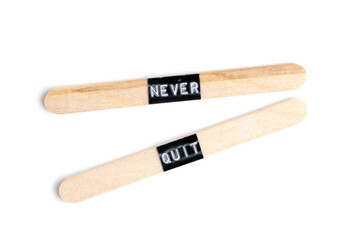 Two wooden chopsticks with word never quit isolated on white background.