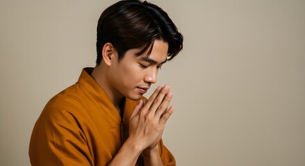 Fototapeta premium Man is praying. Southeast asian man tilting forward with palms joined in a respectful gesture showing calm humility with eyes shut