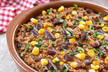 Traditional Mexican Chili con carne. Minced meat and vegetables stew in tomato sauce on wooden table. Close up