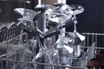 Wine glasses in dishwasher. Clean and tidy. Organizing dishes on holder, loading dirty items.