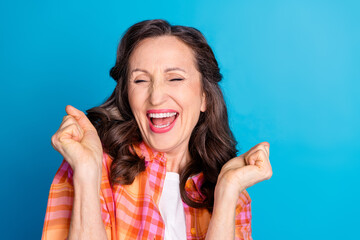 Mature woman expressing enthusiasm with joyful gestures and a cheerful smile against a vibrant blue...