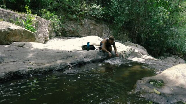 A tourist washes from a mountain stream in the heat