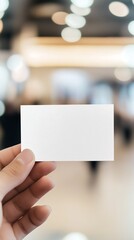 Hand holding a blank card in a busy indoor environment