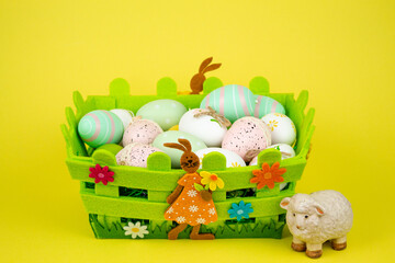 Colorful Easter eggs in a green basket on a yellow background. Easter Feast