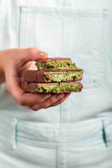 Dubai chocolate bar with filling made of kataifi (knafeh, kadayif) and pistachio  paste. Trendy Dubai chocolate in women's hands.