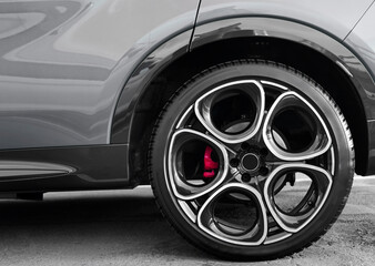 View of Wheel tyre on black car. Modern vehicle wheel with light alloy disc and low profile tire....