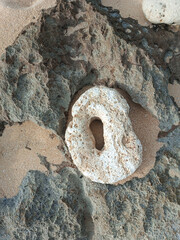 A large rock with a hole on the beach. Natural stone texture top view