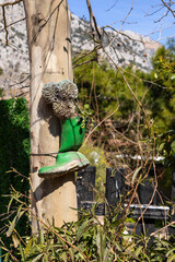 Green rubber boot hanging on tree with decorative elements in a sunny garden setting