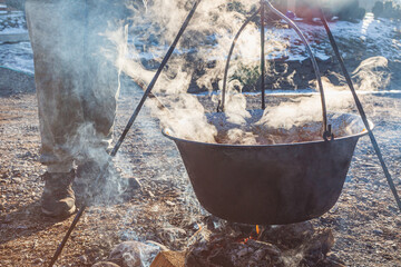 Outdoor Cooking with a Large Pot Over an Open Fire in a Rustic Winter Landscape