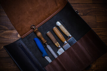Knife Set in Leather Case Displayed on Wooden Table Surface Under Dim Lighting