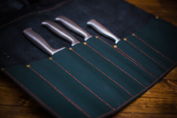 Professional Chef's Knives In Elegant Leather Holder on a Wooden Surface Closeup