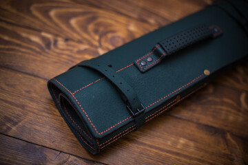 Elegant Green Leather Roll With Red Stitching on Wooden Surface for Organization