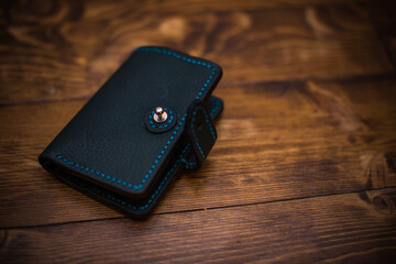 Close-Up of a Stylish Leather Wallet with Blue Stitching on Wooden Surface