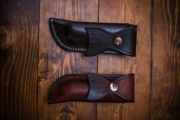 Hand-Crafted Leather Knife Sheaths Displayed on Wooden Background in Black and Brown Variants