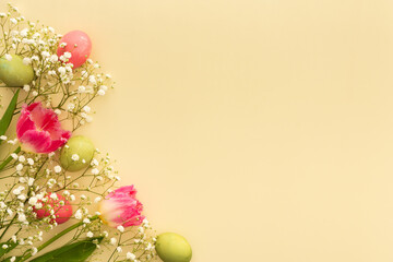 Spring Easter background, multi-colored Easter eggs with tulips and gypsophila on a yellow...