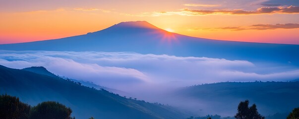 Fototapeta premium A beautiful sunrise over Mount Kilimanjaro, with layers of mist rolling through the valleys below