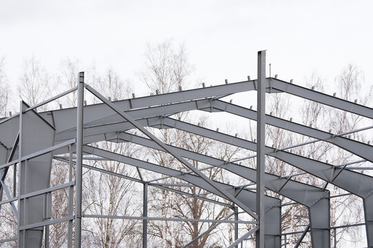Metal construction, in the photo the structure of the building frame made of metal beams against the background of a gray sky