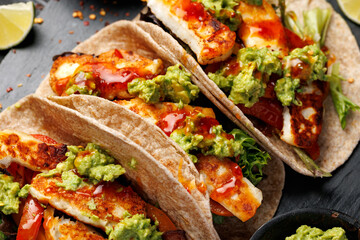 Fried halloumi fajitas with pan roasted onions and bell peppers, avocado guacamole and pickled jalapeno peppers