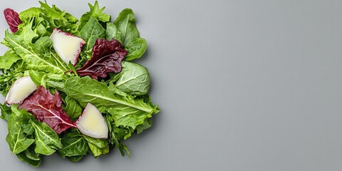 Fresh salad mix with vibrant greens, radishes and red leaf lettuce on a gray background, healthy eating.