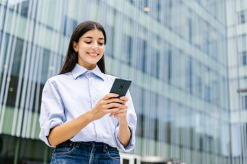 Fototapeta premium Portrait of a successful business woman using cell phone over corporate modern business building
