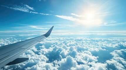 Beautiful Aerial View Over Soft White Clouds and Clear Blue Sky from an Airplane Wing with Sunlight Illuminating the Scenic Horizon