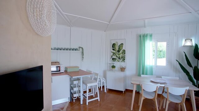 Bright boho-style dining and kitchen space with white wooden walls, minimalist furniture, and natural decor. Soft pastel tones Concept of modern home interior and cozy living