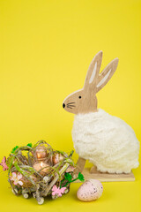 Nest with Easter eggs and a rabbit on a yellow background. Easter eggs