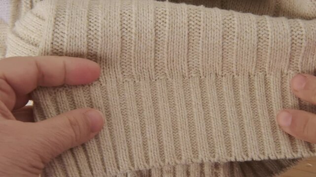 female Hand touching knitted wool cloth or warm fluffy sweater, Handcraft knitting woolen fabric surface, tactile properties, fabric testing