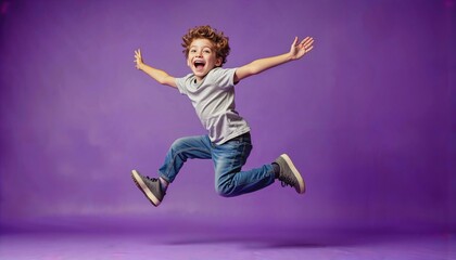 Obraz premium Boy joyfully leaping against a vibrant purple studio backdrop