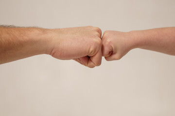 Obraz premium Fist bump between adult and child symbolizing friendship and connection in a neutral background setting