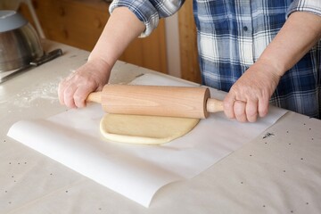 woman rolls out dough with a rolling pin