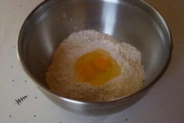 Flour and cracked eggs in a metal bowl