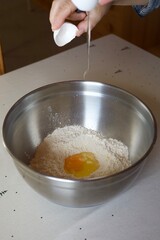 woman breaking an egg into a bowl of flour