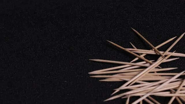 Close-up of a pile of toothpicks falling on a black textured surface