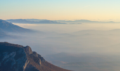 Mountain peak in the early morning against the background of pre-dawn fog