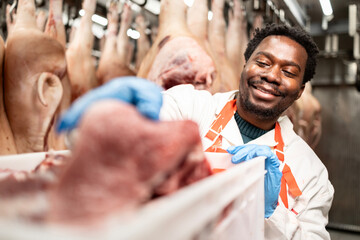 Slaughterhouse worker sorting and packing meat slices in food factory.