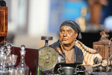 Lively flea market scene in France with vintage items, antiques, books, and decorations. People...