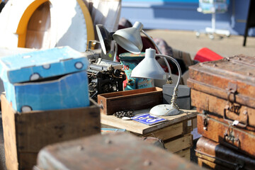Lively flea market scene in France with vintage items, antiques, books, and decorations. People...