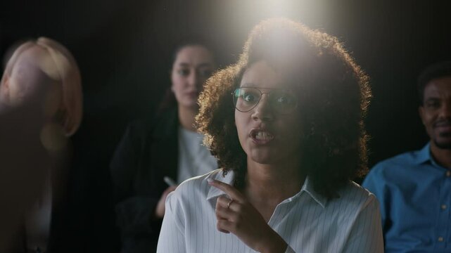 Young African American woman asking question to her colleague during business conference