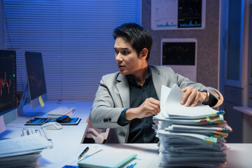 Stressed professional reviewing financial documents surrounded by sticky notes, working late with...