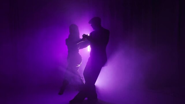 
Under red and orange lights, a tango instructor and student bring the stage to life with rhythmic movements. Their silhouettes reflect the elegance and passion of the dance.