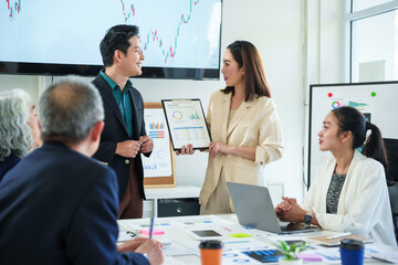 Asian business professionals reviewing financial data, collaborating on performance metrics and strategic planning within contemporary corporate workspace