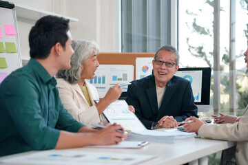 Diverse business team collaborating during strategic meeting, analyzing financial charts, discussing project data with professional interaction and teamwork
