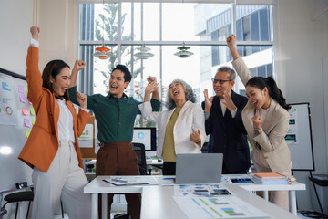 Professional team members cheering together, expressing shared excitement and unity after...