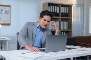 Obraz premium Professional stressed while working, clutching head near laptop, exhibiting tension from overwhelming workload in contemporary office setting