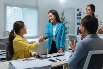 Asian businesswomen concluding partnership, colleagues clapping during celebration of successful negotiation in corporate workplace setting