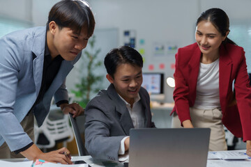 Business team analyzing data on laptop, collaborative Asian professionals discussing workplace strategies with focused teamwork