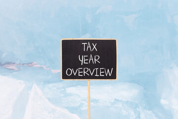 Tax year overview symbol. Concept words Tax year overview on beautiful black yellow blackboard. Beautiful blue Baikal ice background. Business tax year overview concept. Copy space.
