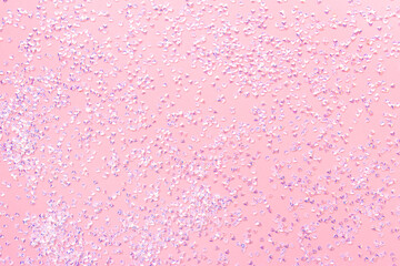 Small silver crystal confetti on a pink background. Festive texture.